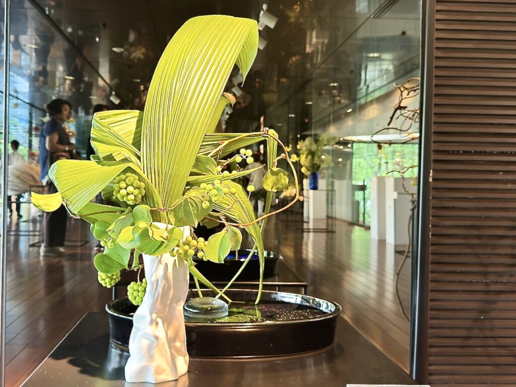 ホログラムシートが水面のようにきらめく、サンキライとカークリコを使った作品(花材:モンステラなど)